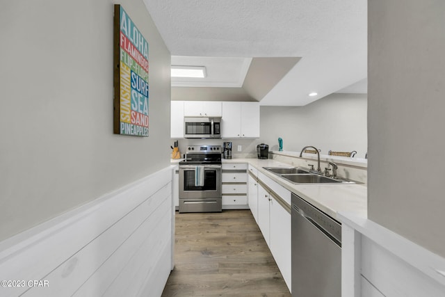 kitchen featuring wood-type flooring, white cabinetry, sink, and appliances with stainless steel finishes