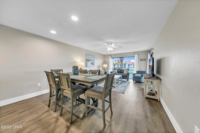 dining area featuring wood-type flooring, a textured ceiling, and ceiling fan