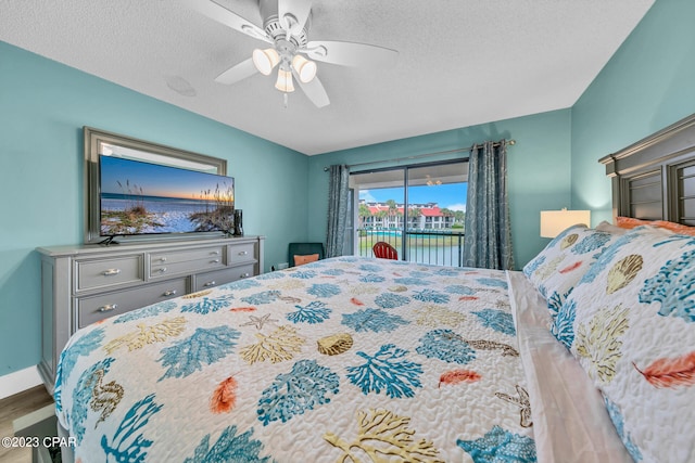 bedroom with access to exterior, ceiling fan, wood-type flooring, and a textured ceiling