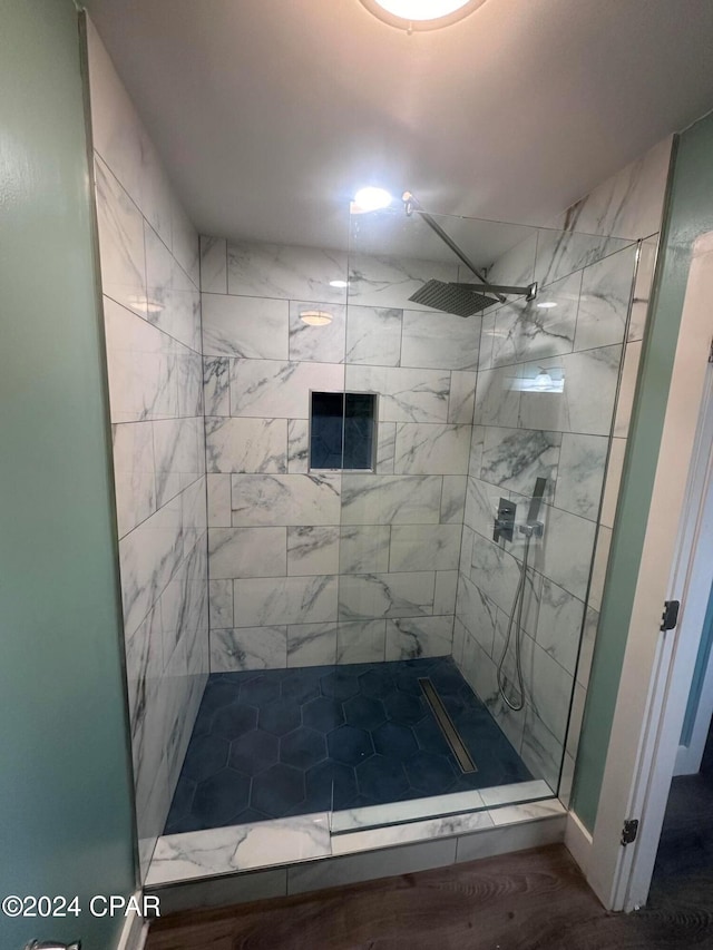 bathroom with a tile shower and hardwood / wood-style floors