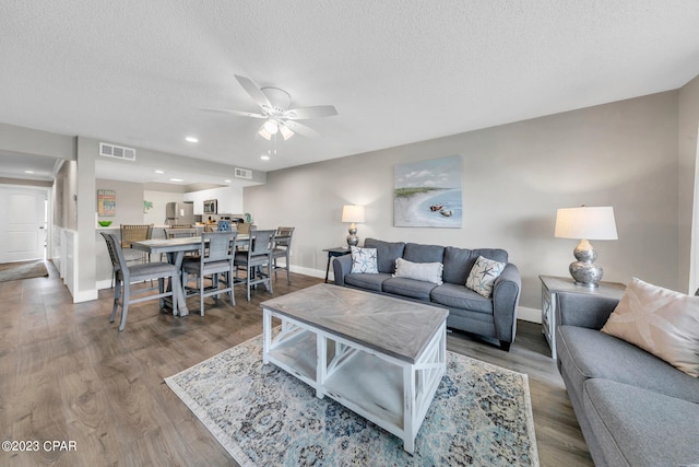 living room with ceiling fan, a textured ceiling, and hardwood / wood-style flooring