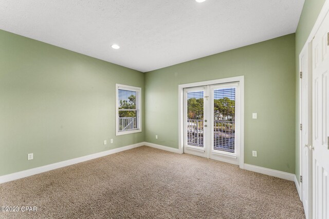 carpeted empty room featuring a textured ceiling and french doors