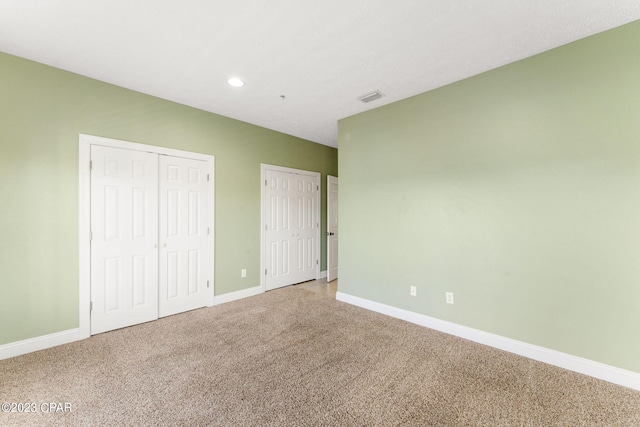 unfurnished bedroom with carpet floors and two closets