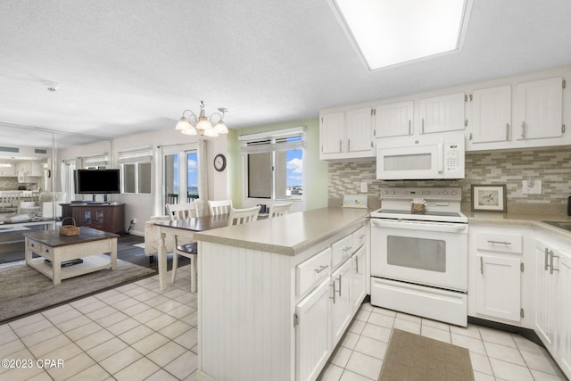 kitchen with white appliances, kitchen peninsula, hanging light fixtures, and white cabinets