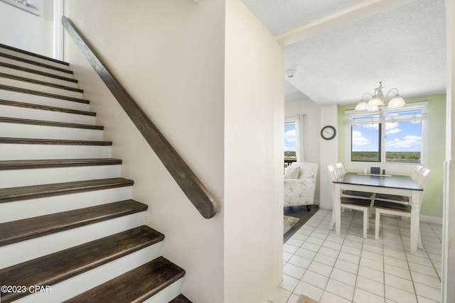 staircase with tile patterned flooring, a chandelier, and a textured ceiling