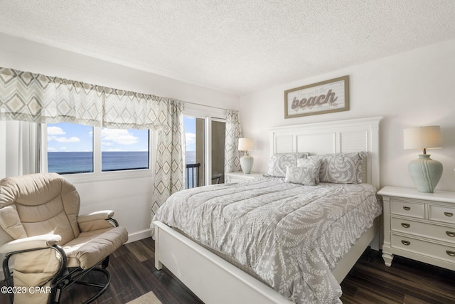 bedroom with a water view, dark hardwood / wood-style floors, and a textured ceiling