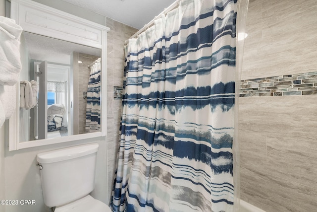 bathroom featuring toilet and curtained shower