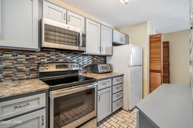 kitchen with appliances with stainless steel finishes, light tile patterned flooring, tasteful backsplash, and light stone counters