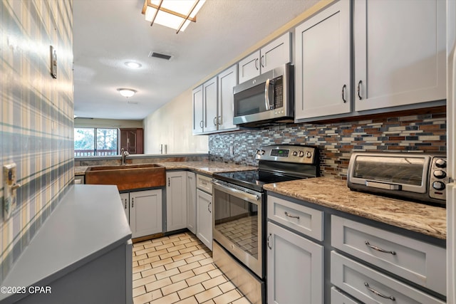 kitchen featuring appliances with stainless steel finishes, light tile patterned flooring, tasteful backsplash, and sink