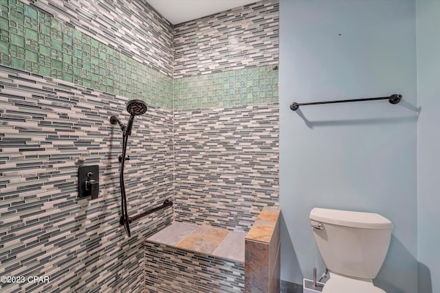 bathroom featuring a tile shower and toilet