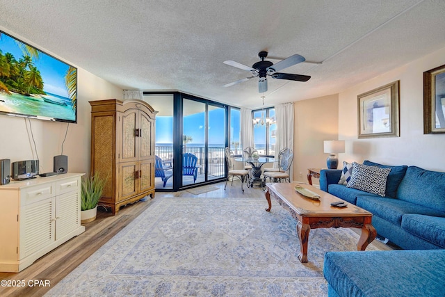 9850 S Thomas Dr Unit 211E, Panama City Beach, FL 32408 - living room with a textured ceiling, ceiling fan, a wall of windows, light wood-type flooring, and a chandelier