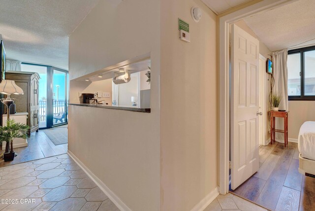 9850 S Thomas Dr Unit 211E, Panama City Beach, FL 32408 - hallway featuring baseboards, a textured ceiling, and light wood finished floors