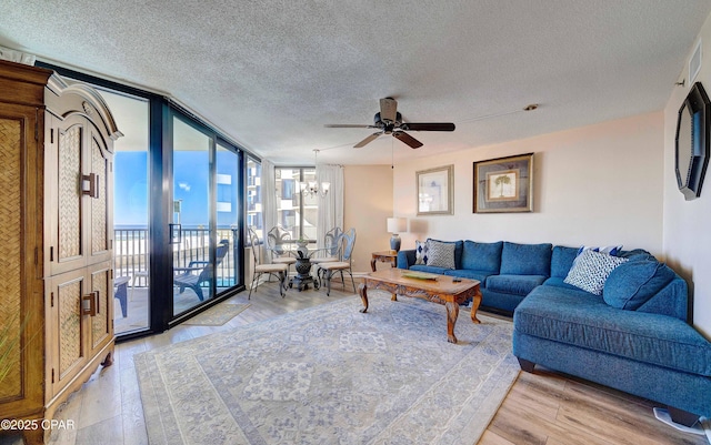 9850 S Thomas Dr Unit 211E, Panama City Beach, FL 32408 - living room featuring a textured ceiling, a wall of windows, light wood-style flooring, a ceiling fan, and a chandelier
