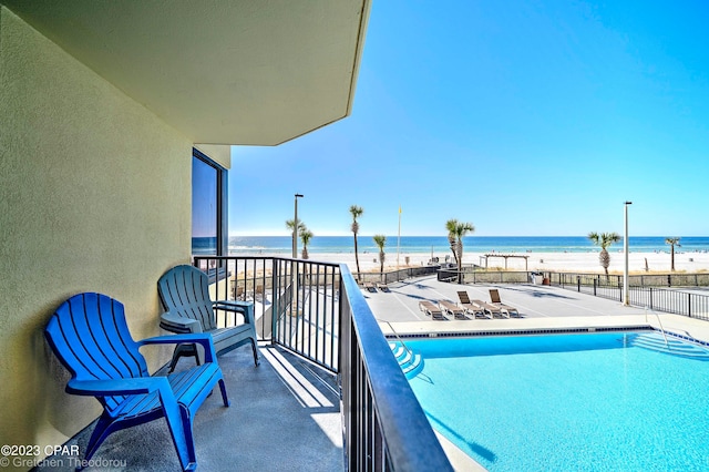 view of swimming pool featuring a water view and a beach view