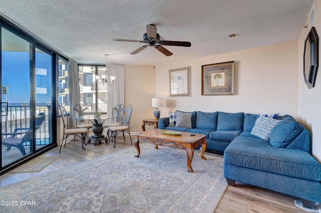 9850 S Thomas Dr Unit 211E, Panama City Beach, FL 32408 - living room featuring a chandelier, wood finished floors, a textured ceiling, a wall of windows, and a ceiling fan