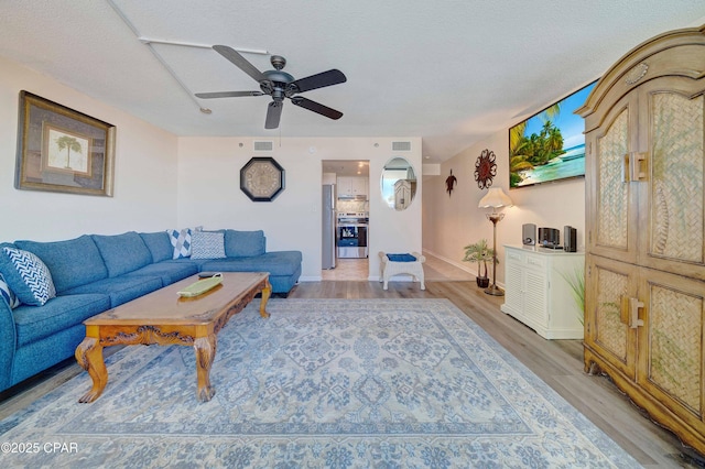 9850 S Thomas Dr Unit 211E, Panama City Beach, FL 32408 - living room featuring baseboards, a ceiling fan, light wood finished floors, and a textured ceiling