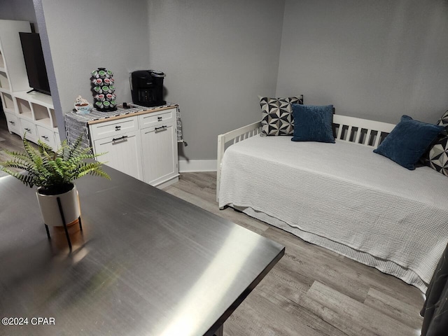 bedroom featuring light wood finished floors and baseboards