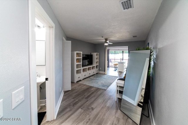 living room with visible vents, light wood-style flooring, a ceiling fan, a textured ceiling, and baseboards