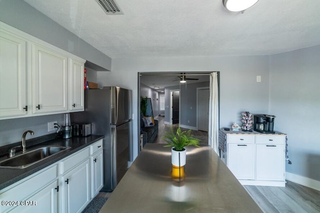 kitchen with visible vents, white cabinets, dark countertops, dark wood-type flooring, and a sink