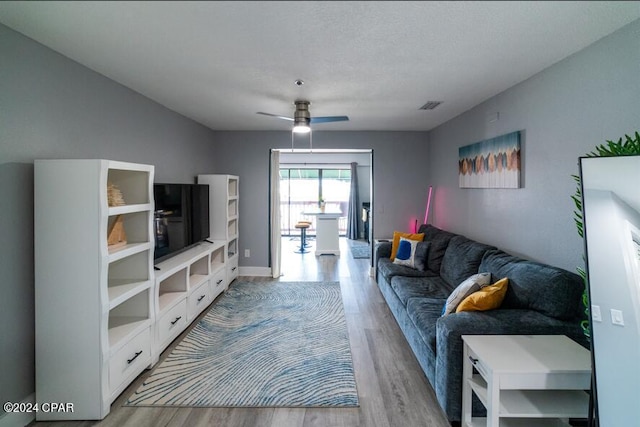 living room featuring ceiling fan, light wood-style flooring, and visible vents