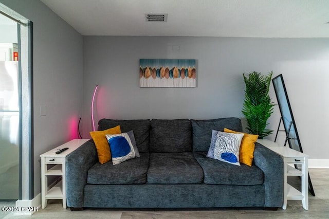 living room with wood finished floors, visible vents, and baseboards