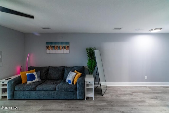 living room with baseboards, visible vents, and wood finished floors