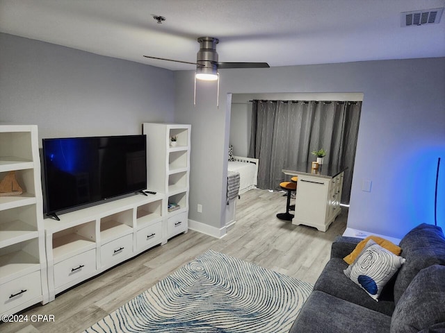 living area featuring light wood-style floors, ceiling fan, visible vents, and baseboards