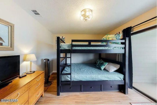 bedroom with a textured ceiling and light hardwood / wood-style flooring