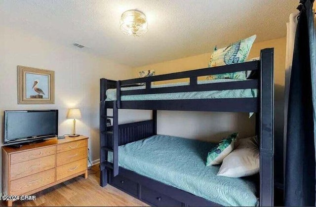 bedroom featuring a textured ceiling and light hardwood / wood-style flooring