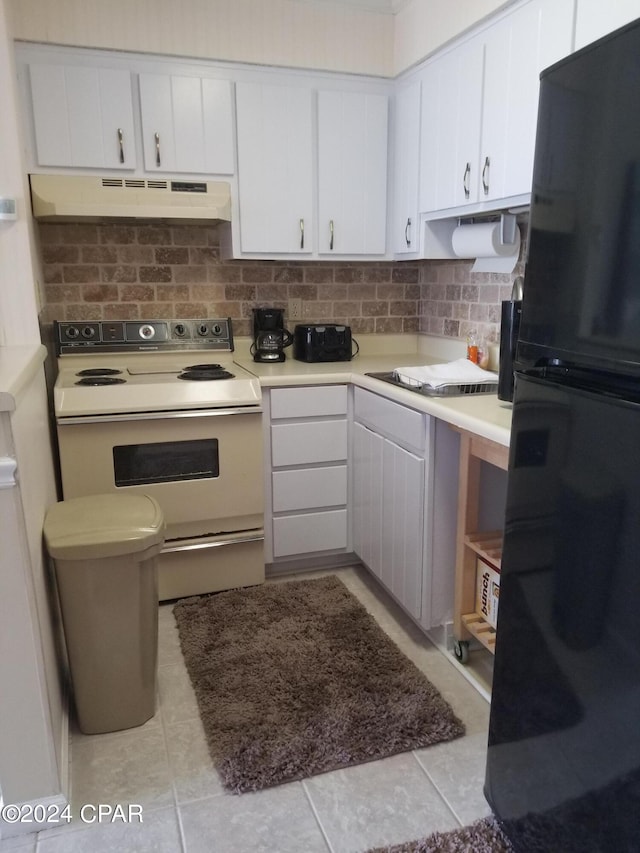 kitchen featuring black fridge, light tile patterned floors, white cabinetry, white electric stove, and decorative backsplash