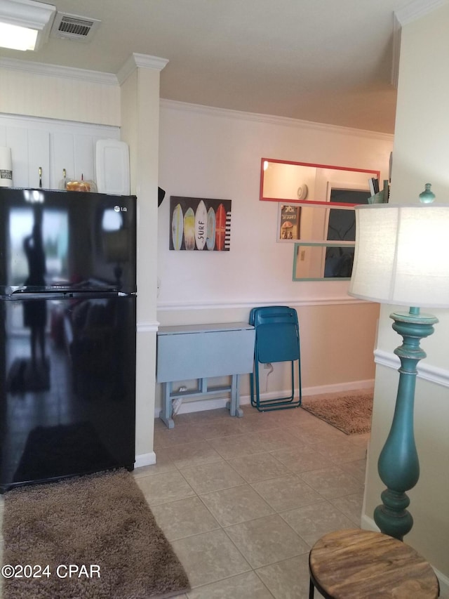 kitchen with ornamental molding, white cabinets, black refrigerator, and light tile patterned flooring