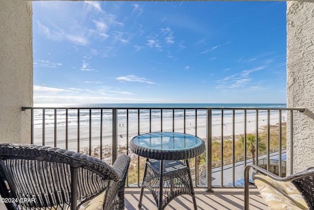 balcony with a water view and a view of the beach