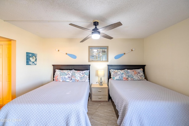 tiled bedroom featuring ceiling fan and a textured ceiling