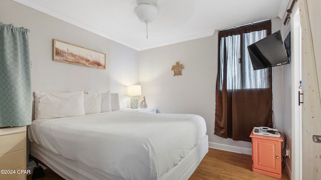 bedroom with crown molding, hardwood / wood-style floors, ceiling fan, and multiple windows