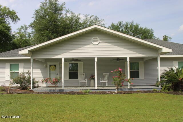 view of front of house featuring ceiling fan, a front lawn, and covered porch