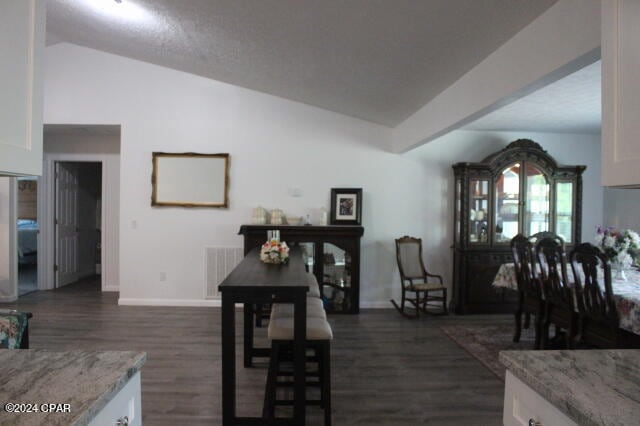 dining space featuring dark hardwood / wood-style flooring and lofted ceiling