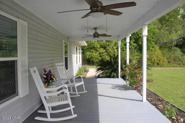 wooden terrace featuring a yard and ceiling fan