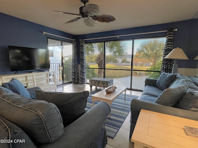 living room with a water view, ceiling fan, and light tile patterned flooring