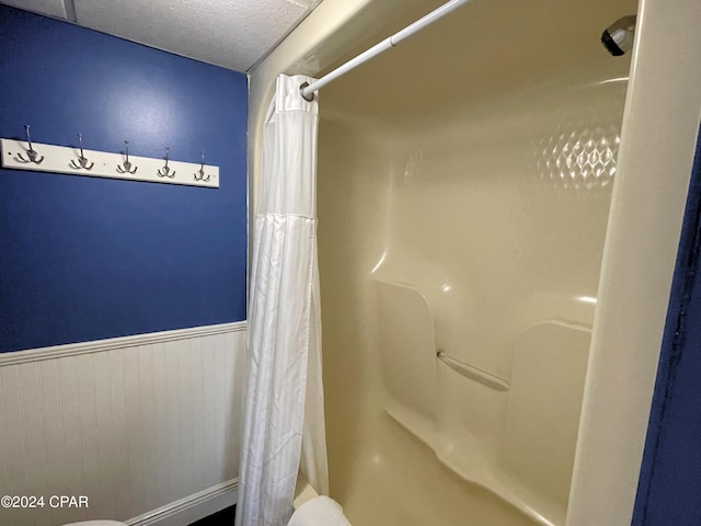 bathroom featuring a shower with curtain, a textured ceiling, toilet, and wooden walls