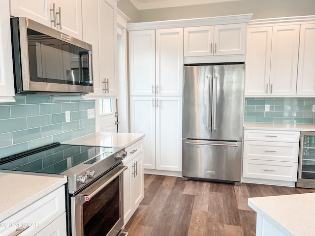 kitchen featuring wine cooler, crown molding, hardwood / wood-style floors, backsplash, and appliances with stainless steel finishes