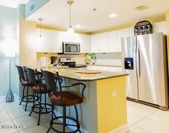 kitchen with white cabinets, hanging light fixtures, a breakfast bar area, and stainless steel appliances