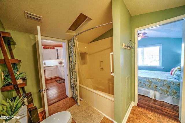 bathroom featuring hardwood / wood-style floors, a textured ceiling, shower / tub combo with curtain, and vaulted ceiling