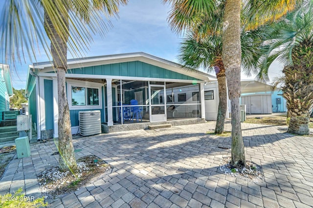 view of front facade with central AC unit, a patio area, and a sunroom