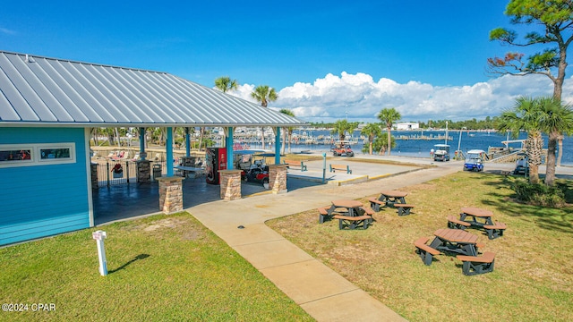 view of home's community with a water view, a lawn, and a boat dock