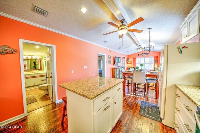 kitchen with a center island, vaulted ceiling, ceiling fan with notable chandelier, white cabinets, and dark hardwood / wood-style floors