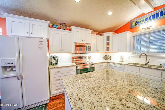 kitchen featuring appliances with stainless steel finishes, vaulted ceiling with beams, backsplash, and sink