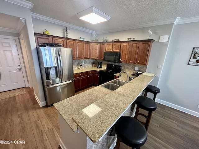 kitchen with a kitchen breakfast bar, wood-type flooring, stainless steel refrigerator with ice dispenser, and range