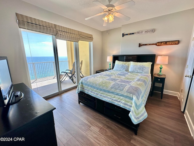 bedroom with a water view, ceiling fan, dark hardwood / wood-style flooring, and multiple windows