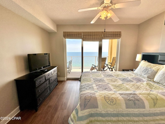 bedroom with a water view, ceiling fan, access to outside, a textured ceiling, and dark hardwood / wood-style flooring