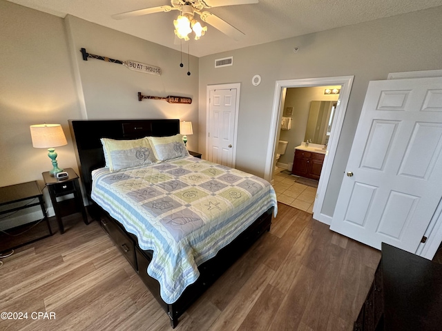 bedroom with connected bathroom, wood-type flooring, and ceiling fan